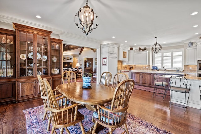 dining room featuring dark hardwood / wood-style flooring, ornamental molding, and a chandelier