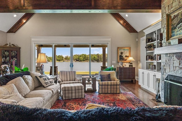living room featuring a stone fireplace, vaulted ceiling with beams, built in features, dark hardwood / wood-style floors, and a water view