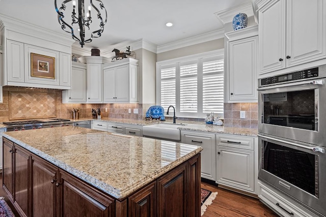 kitchen featuring stainless steel appliances, sink, white cabinets, and hanging light fixtures