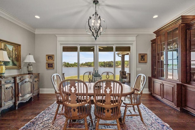 dining area featuring crown molding, a water view, dark wood-type flooring, and a notable chandelier