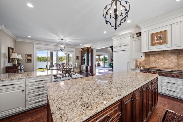 kitchen featuring decorative light fixtures, a kitchen island, stainless steel gas cooktop, and white cabinetry