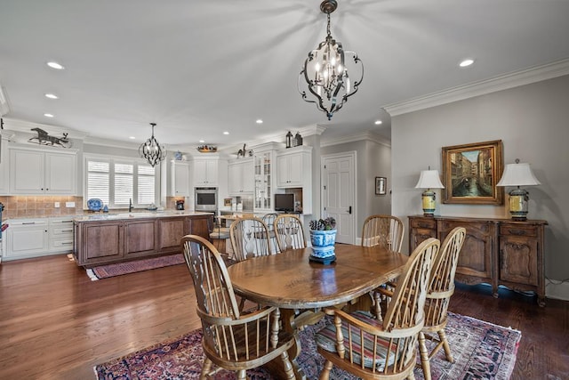 dining area with a chandelier, crown molding, sink, and dark wood-type flooring