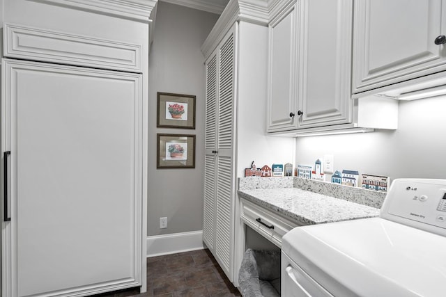 clothes washing area featuring cabinets, washer / dryer, and ornamental molding