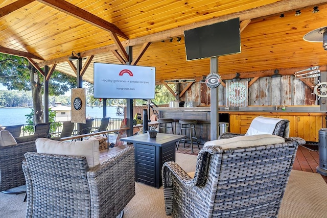 living room featuring vaulted ceiling with beams, wood walls, sink, and wood ceiling