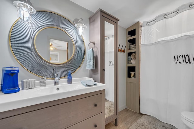 bathroom featuring vanity, ceiling fan, toilet, built in features, and wood-type flooring