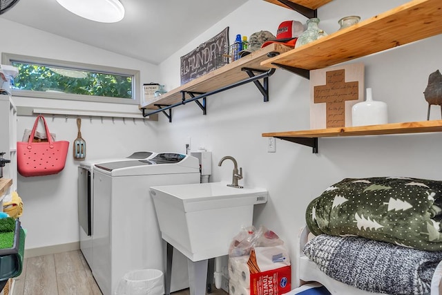 washroom featuring separate washer and dryer, sink, and light hardwood / wood-style floors