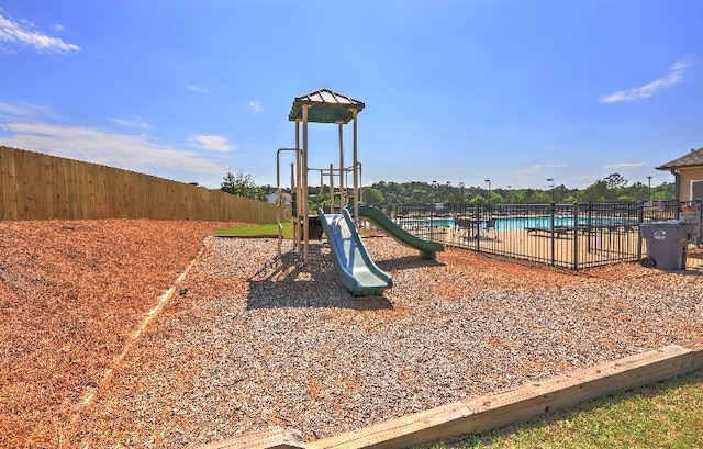 community jungle gym with fence and a community pool