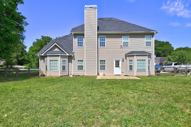 back of house with fence, roof with shingles, a chimney, a patio area, and a yard