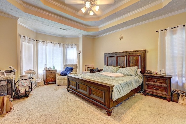 bedroom featuring crown molding, a tray ceiling, light colored carpet, and ceiling fan