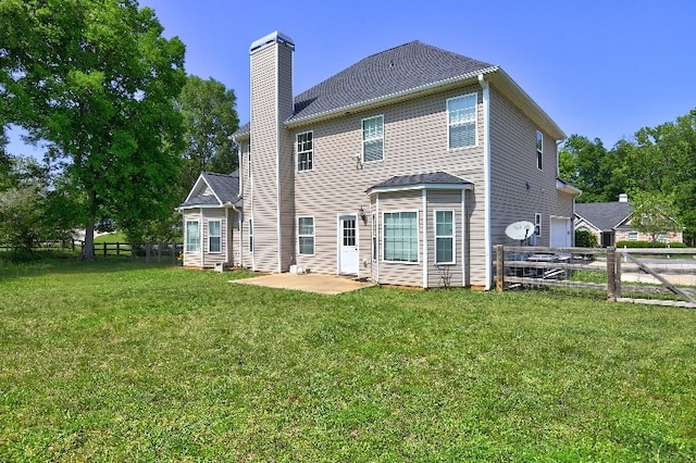 rear view of house with a lawn, a fenced backyard, a chimney, and a patio