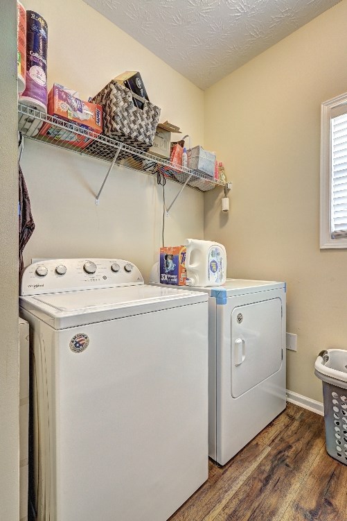 washroom featuring baseboards, laundry area, wood finished floors, and washer and clothes dryer