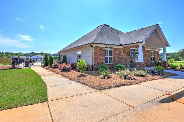 view of side of property with a lawn, brick siding, fence, and a gate