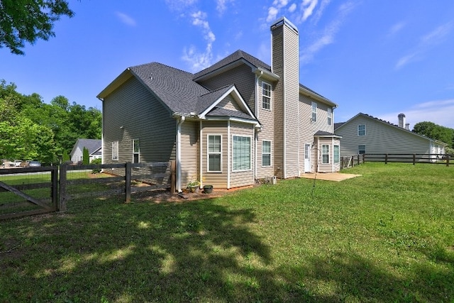 rear view of property featuring fence, a chimney, a yard, and a patio area