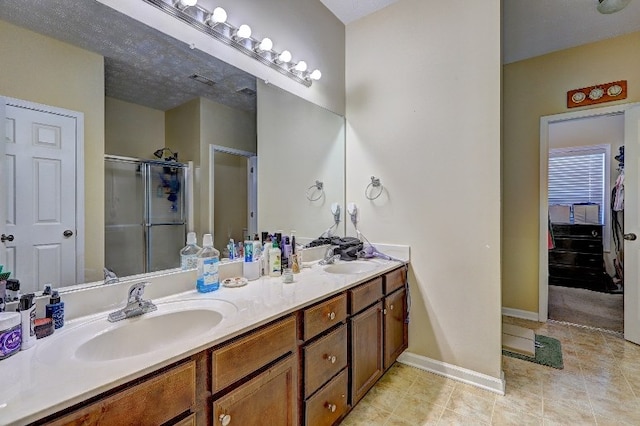 full bathroom featuring a sink, tile patterned flooring, a stall shower, and double vanity