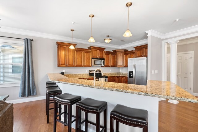 222 Sheffield Dr Unit E-5, Sparta, GA 31087 - kitchen featuring a peninsula, ornamental molding, a breakfast bar, appliances with stainless steel finishes, and brown cabinets
