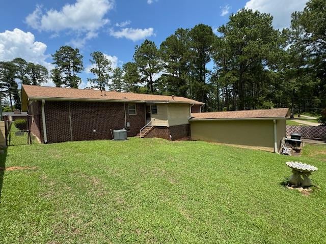 back of property featuring a lawn and central AC