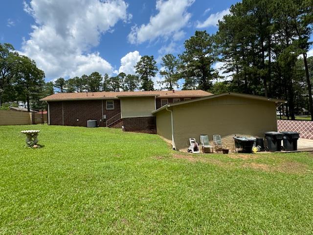 rear view of property featuring a lawn and central AC