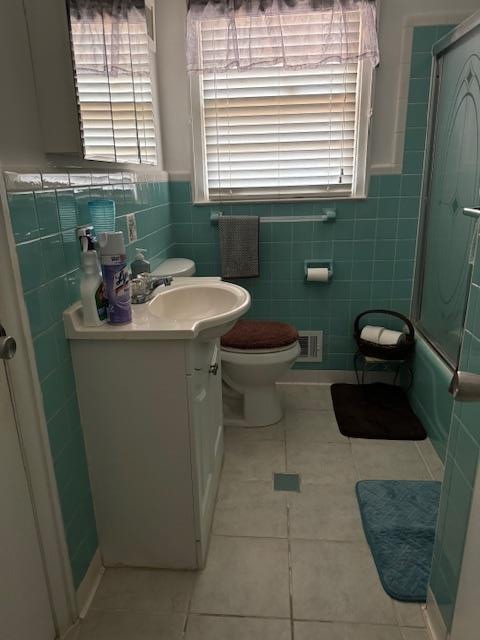 full bathroom with tile patterned floors, vanity, tile walls, enclosed tub / shower combo, and toilet