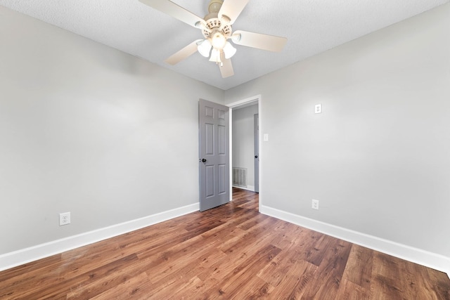 spare room with ceiling fan, dark wood-style flooring, visible vents, and baseboards