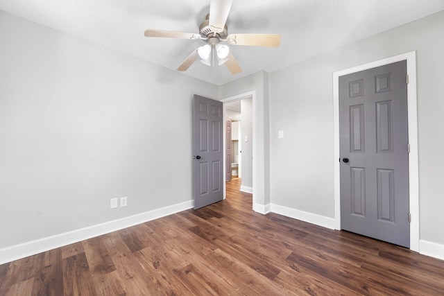 unfurnished bedroom featuring dark wood-style floors, baseboards, and a ceiling fan