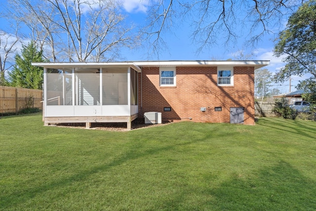 rear view of property featuring brick siding, fence, a sunroom, a yard, and crawl space