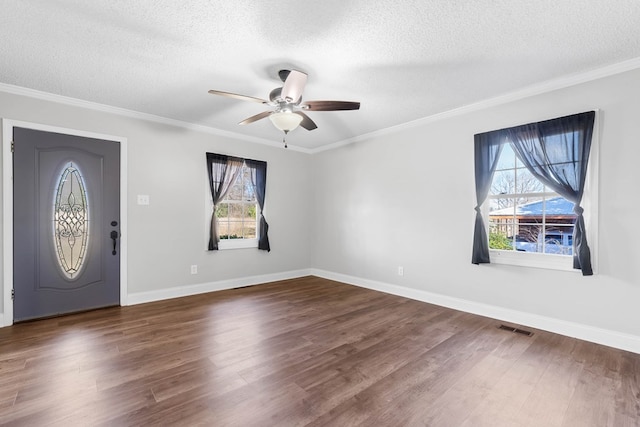 foyer entrance with dark wood-style floors, visible vents, and crown molding