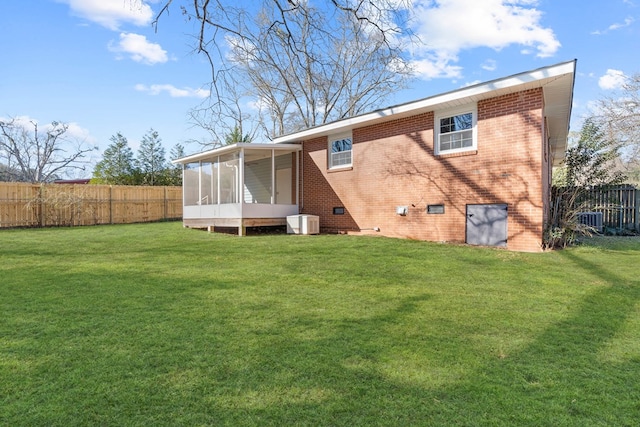 rear view of house with a sunroom, fence, a lawn, and brick siding