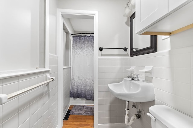 full bathroom with a wainscoted wall, tile walls, toilet, a sink, and wood finished floors