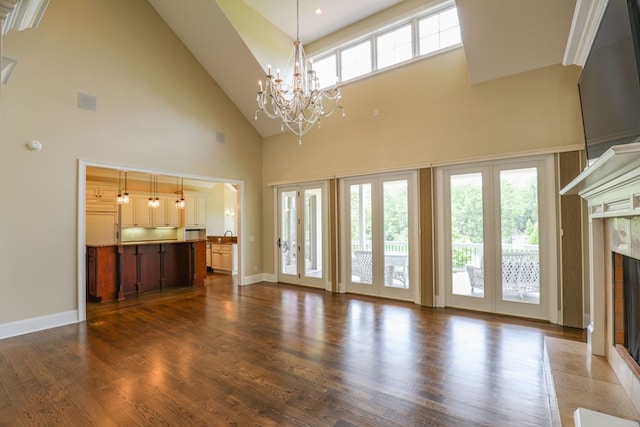 unfurnished living room featuring a fireplace, dark hardwood / wood-style flooring, a towering ceiling, and a notable chandelier