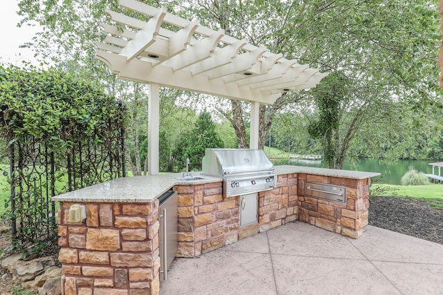 view of patio / terrace with a pergola, a water view, exterior kitchen, and grilling area