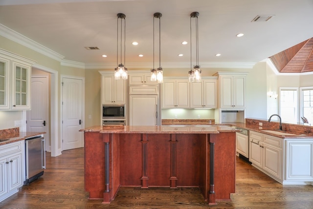 kitchen featuring a kitchen breakfast bar, built in appliances, a kitchen island, and hanging light fixtures