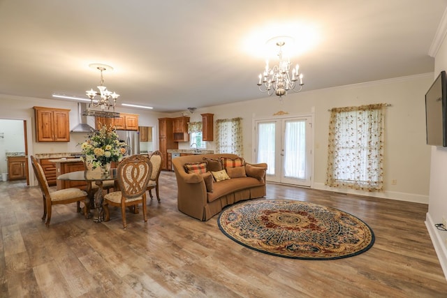 living room with french doors, sink, an inviting chandelier, crown molding, and hardwood / wood-style flooring