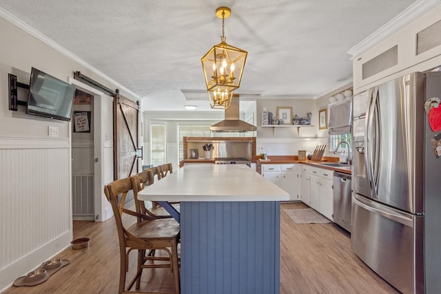 3657 Sussex Dr, Milledgeville, GA 31061 - kitchen featuring range hood, a barn door, white cabinetry, a sink, and appliances with stainless steel finishes