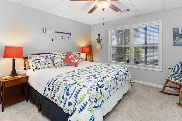 bedroom with ceiling fan, light colored carpet, and a paneled ceiling