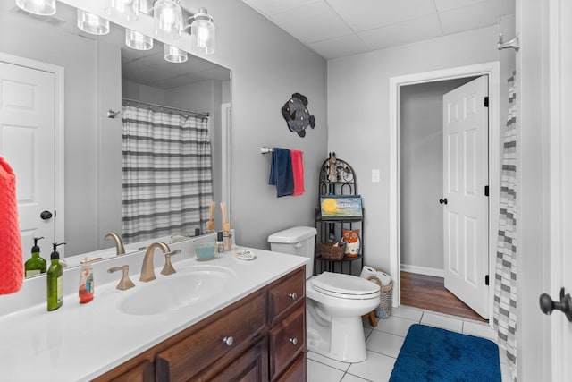 bathroom featuring tile patterned flooring, vanity, a paneled ceiling, and toilet