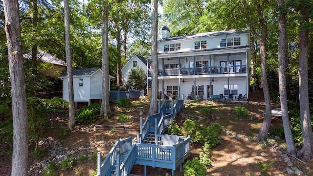 rear view of house with ceiling fan, a balcony, and a storage unit