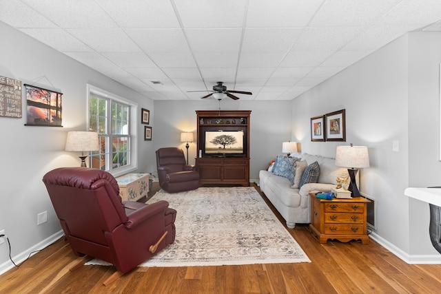 living room featuring hardwood / wood-style flooring, a paneled ceiling, and ceiling fan