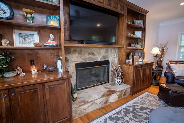 living room featuring ornamental molding, a fireplace, and light wood-type flooring