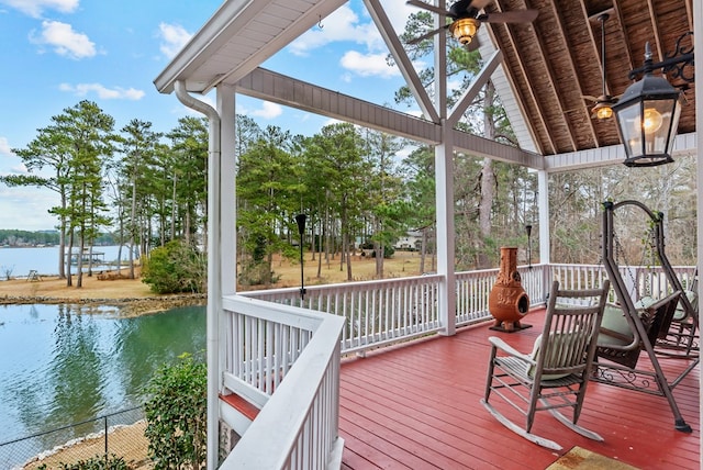 deck with ceiling fan and a water view