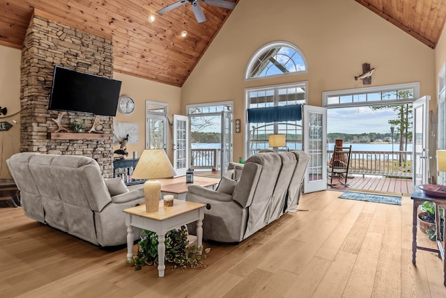 living room featuring a towering ceiling, a water view, ceiling fan, wooden ceiling, and light hardwood / wood-style flooring