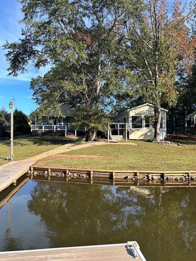 view of dock with a lawn and a water view