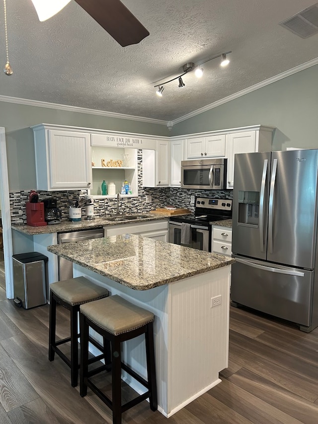 kitchen featuring a center island, backsplash, white cabinets, sink, and appliances with stainless steel finishes