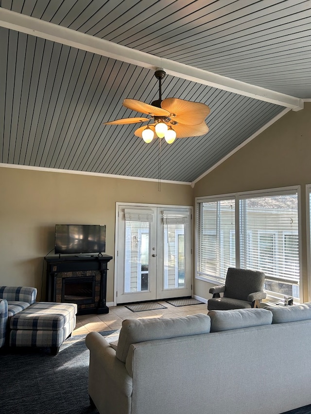 living room with a stone fireplace, ceiling fan, french doors, and lofted ceiling with beams