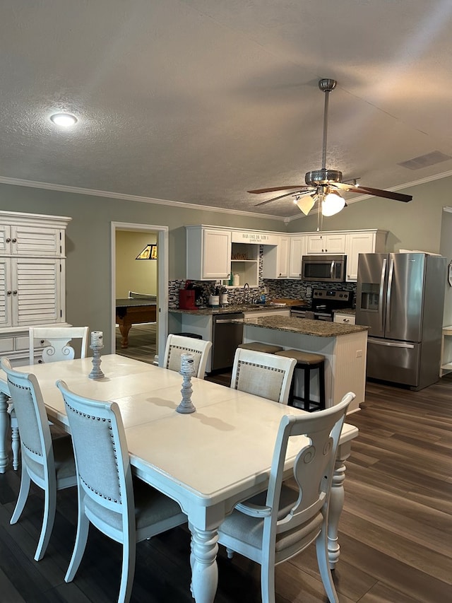 dining room with a textured ceiling, dark hardwood / wood-style floors, crown molding, and pool table