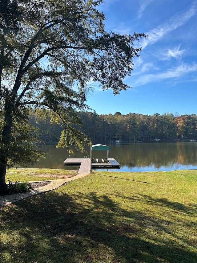 view of dock with a yard and a water view