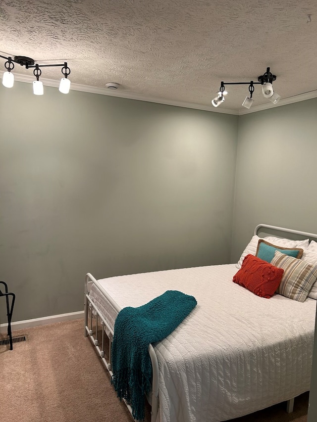 bedroom with carpet, rail lighting, crown molding, and a textured ceiling