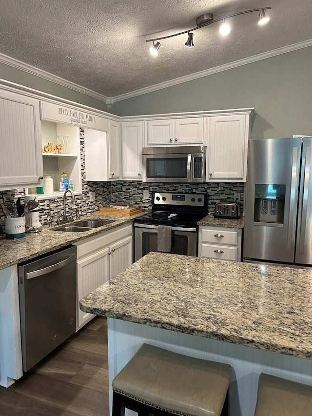 kitchen with tasteful backsplash, white cabinetry, stainless steel appliances, and light stone counters