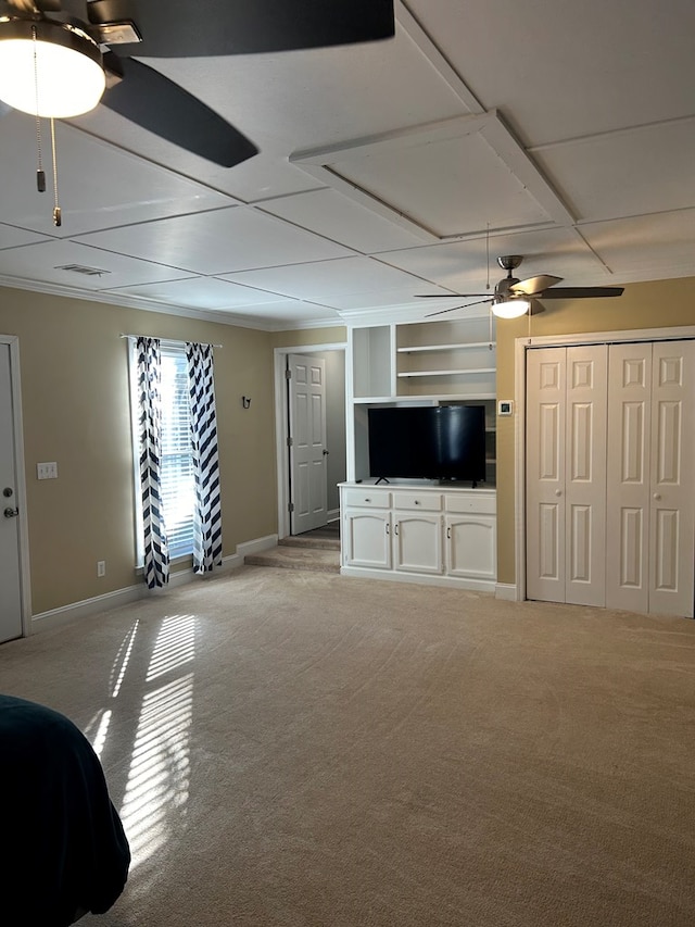 unfurnished living room featuring built in shelves, ceiling fan, and light colored carpet