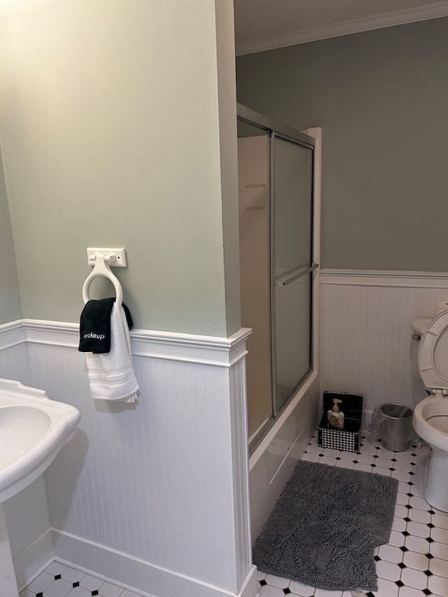 bathroom featuring ornamental molding, tile patterned flooring, enclosed tub / shower combo, and toilet