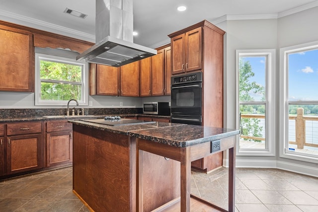 kitchen with island range hood, crown molding, black appliances, dark stone countertops, and a kitchen island